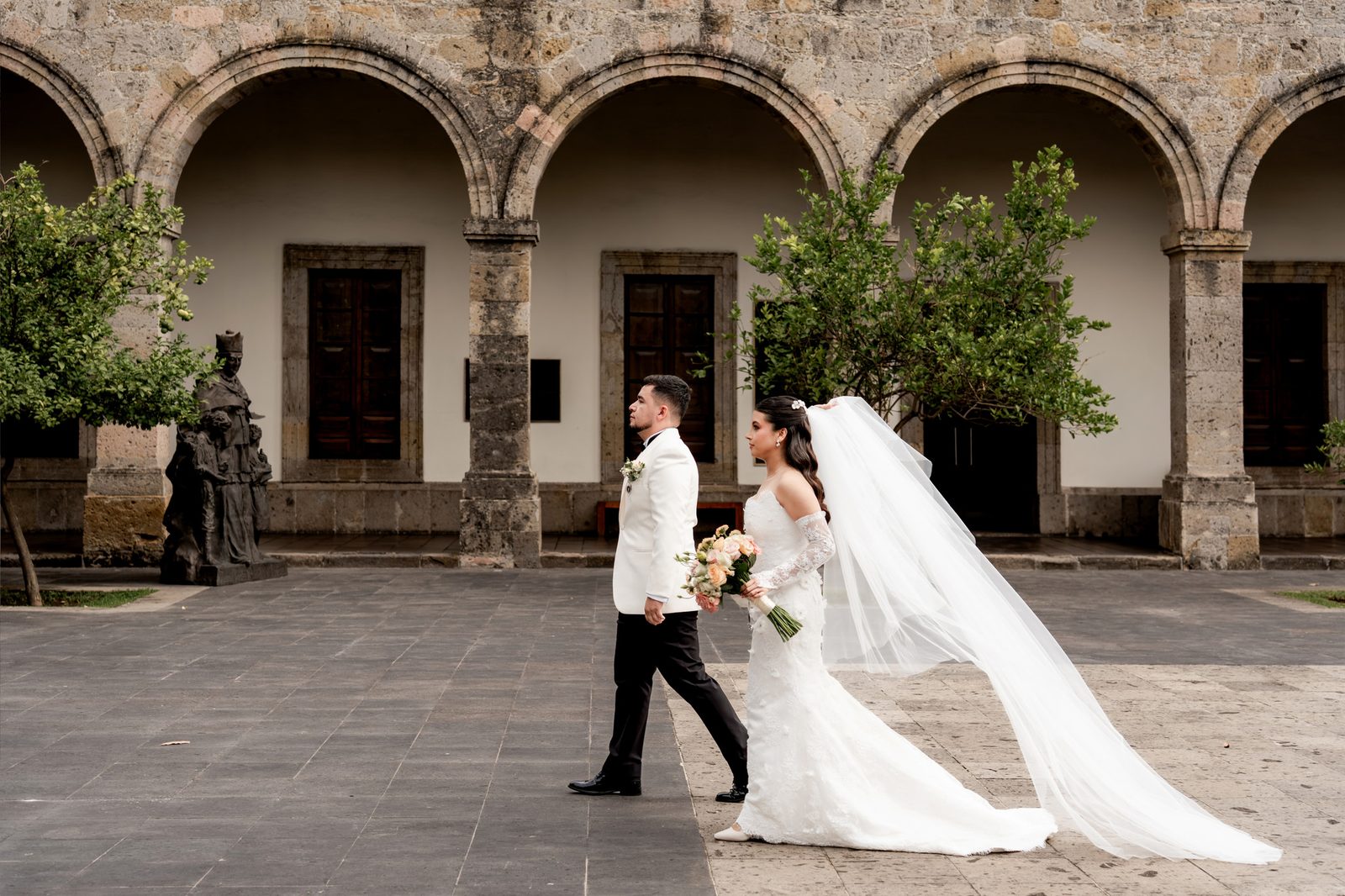 Larissa y Octavio caminando por los arcos de cantera antes de su boda en Tonalá